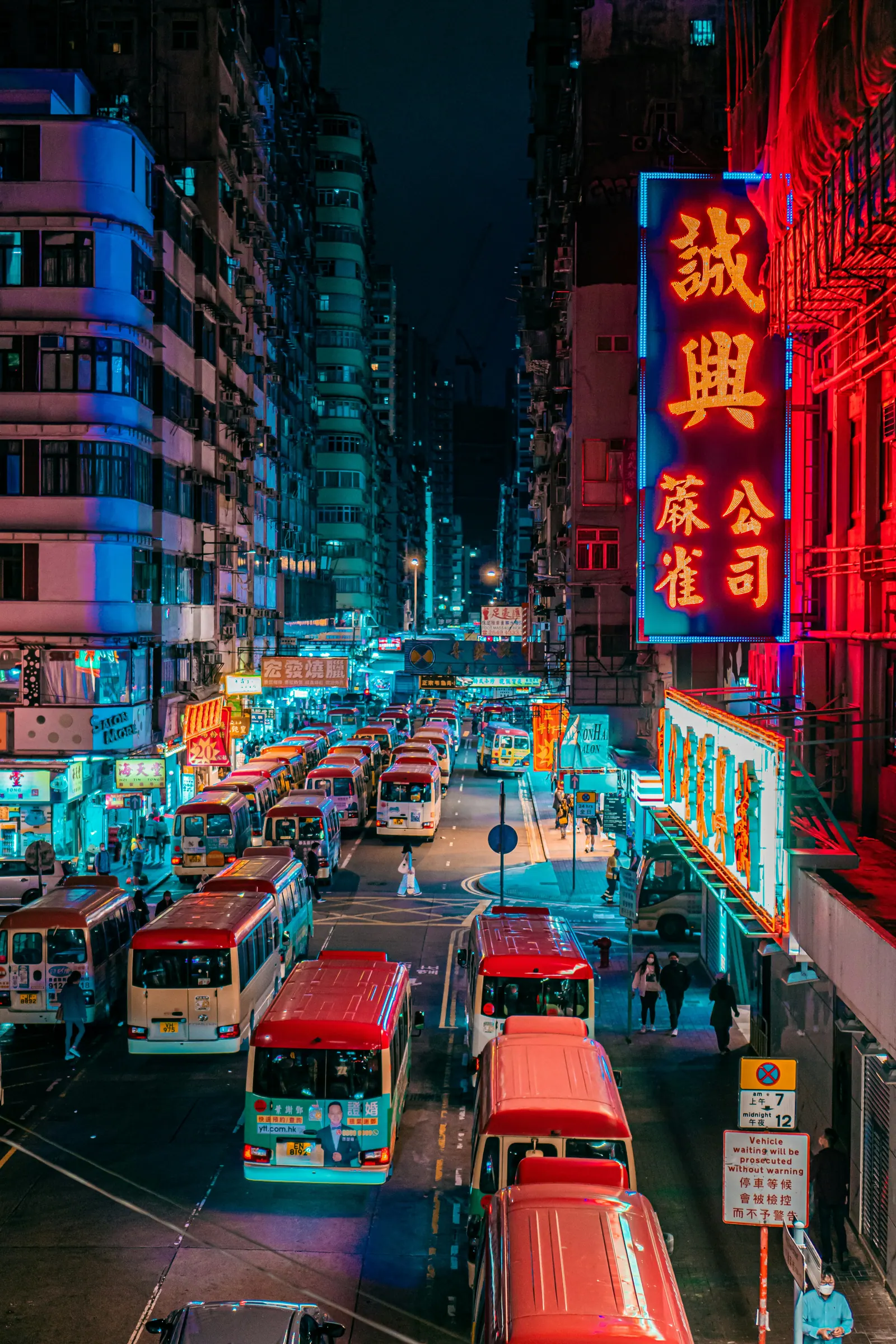 Hong Kong street at night with neon signs and red taxis