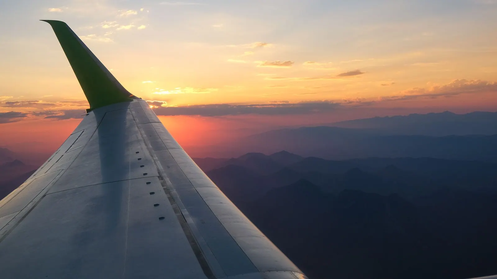 Aircraft wing above the clouds at golden hour